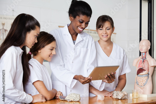 Photo: Teacher With Teenage Girls Using Digital Tablet At Desk Teacher With Teenage Girls Using Digital Tablet At Desk