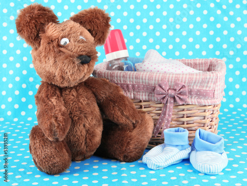 Photo: Beautiful basket of baby clothes on a blue background Beautiful basket of baby clothes on a blue background