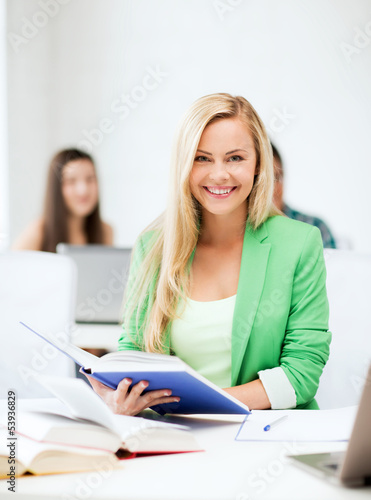 Photo: smiling young woman reading book at school smiling young woman reading book at school