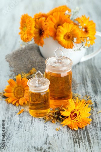 Photo: Medicine bottles and calendula flowers on wooden background Medicine bottles and calendula flowers on wooden background