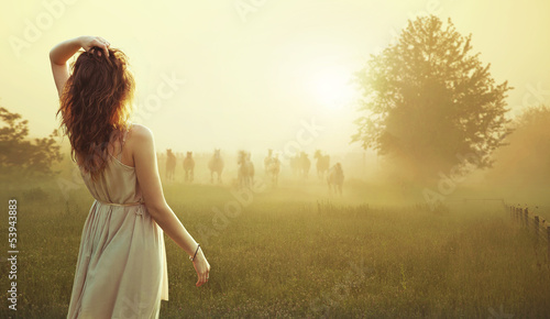 Photo: Young brunette lady watching herd of horses Young brunette lady watching herd of horses