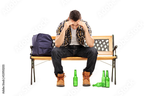 Photo: Young man with hangover sitting on a bench Young man with hangover sitting on a bench