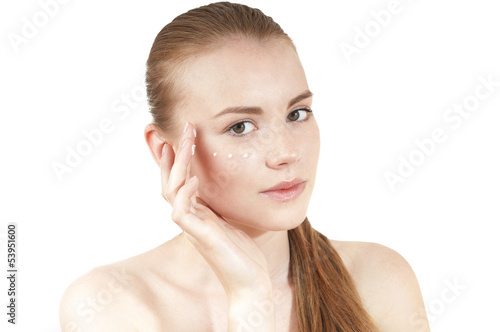 Photo: Young girl applying moisturizer cream on her face. Isolated Young girl applying moisturizer cream on her face. Isolated