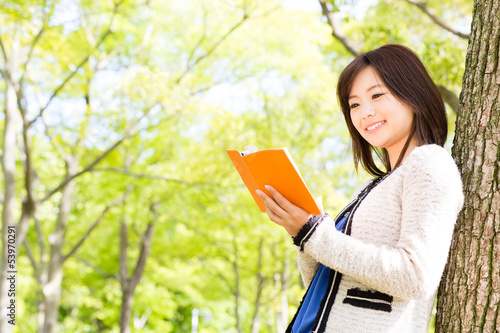Photo: young asian woman reading book in the park young asian woman reading book in the park