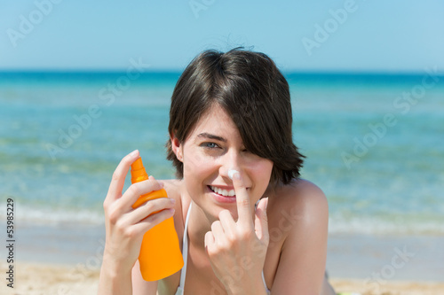 Photo: frau am strand cremt sich das gesicht mit sonnencreme ein frau am strand cremt sich das gesicht mit sonnencreme ein