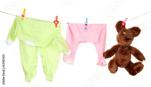 Photo: Baby clothes hanging on clothesline, isolated on white Baby clothes hanging on clothesline, isolated on white