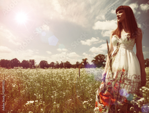 Photo: Beauty young woman walking around the summer meadow Beauty young woman walking around the summer meadow