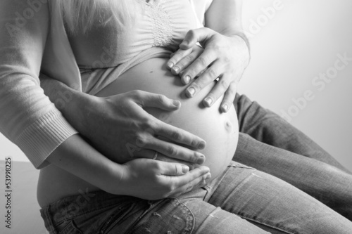 Photo: Pregnant woman with husband sitting on floor, holding hands on Pregnant woman with husband sitting on floor, holding hands on