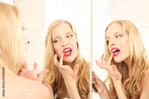 Photo: junge Frau trägt Lippenstift auf junge Frau trägt Lippenstift auf