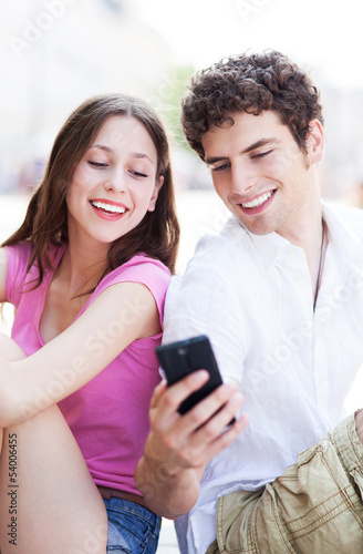 Photo: Young couple looking at mobile phone Young couple looking at mobile phone