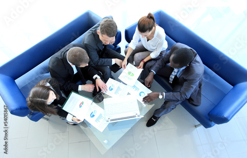 Photo: Top view of working business group sitting at table Top view of working business group sitting at table