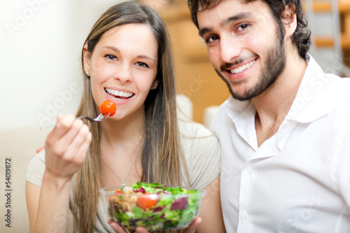 Photo: Couple eating a salad in the living room Couple eating a salad in the living room