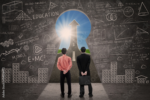 Photo: Business partners looking up arrow sign through key hole Business partners looking up arrow sign through key hole