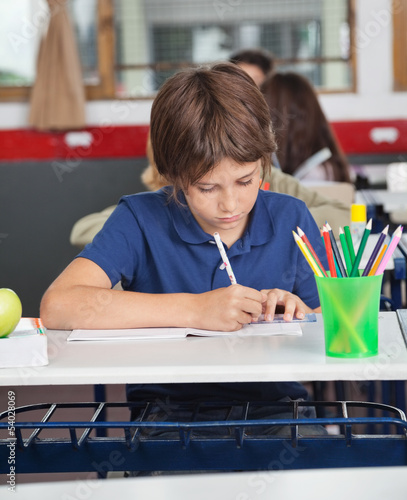 Photo: Little Schoolboy Studying At Desk Little Schoolboy Studying At Desk