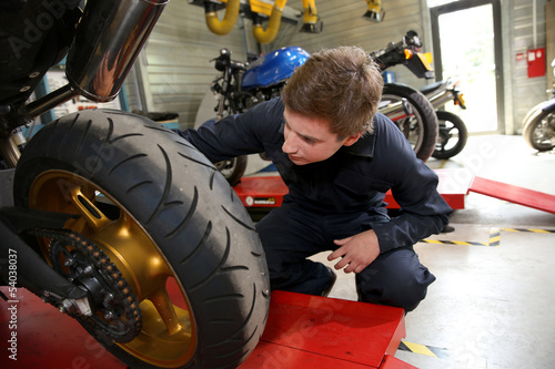 Photo: Teenager in professional training, repairing motorbike Teenager in professional training, repairing motorbike