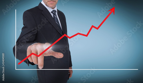 Photo: Businessman selecting a red arrow pointing up on a chart Businessman selecting a red arrow pointing up on a chart