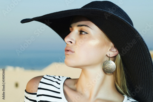 Photo: Beautiful woman in hat on the roof of Santorini island Beautiful woman in hat on the roof of Santorini island