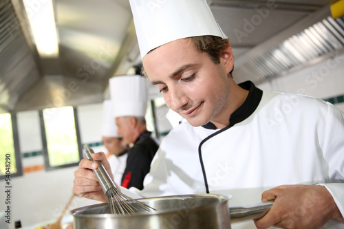 Photo: Young cook in restaurant kitchen preparing sauce Young cook in restaurant kitchen preparing sauce