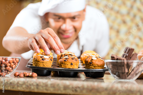 Photo: Asian man baking muffins in home kitchen Asian man baking muffins in home kitchen