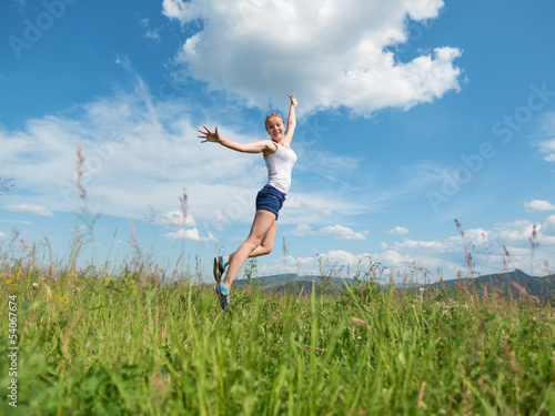 Photo: The girl jumps on a green grass The girl jumps on a green grass