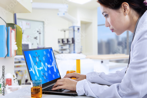 Photo: Attractive doctor working with laptop in lab Attractive doctor working with laptop in lab
