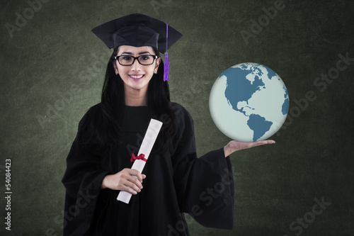 Photo: Beautiful female graduate holding world globe in class Beautiful female graduate holding world globe in class