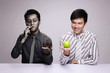 Foto: Businessman smoking while holding rotten apple, another businessman holding a fresh green apple Businessman smoking while holding rotten apple, another businessman holding a fresh green apple