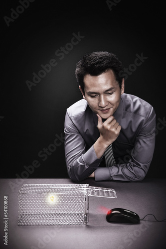 Photo: Businessman waiting for computer mouse to get into mouse trap Businessman waiting for computer mouse to get into mouse trap