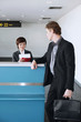 Photo: Airline check-in attendant checking businessman's passport at the airport check-in counter Airline check-in attendant checking businessman's passport at the airport check-in counter