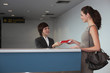 Photo: Airline check-in attendant returning businesswoman's passport at the airport check-in counter Airline check-in attendant returning businesswoman's passport at the airport check-in counter