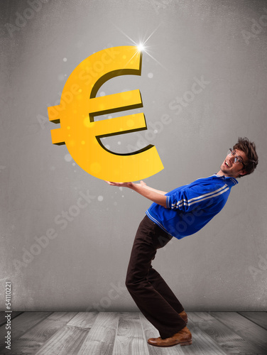 Photo: Good-looking boy holding a big 3d gold euro sign Good-looking boy holding a big 3d gold euro sign