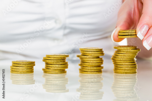 Photo: Frau mit Münzstapel beim Geld sparen Frau mit Münzstapel beim Geld sparen