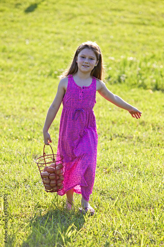 Photo: Young girl carrying brown eggs in a basket Young girl carrying brown eggs in a basket