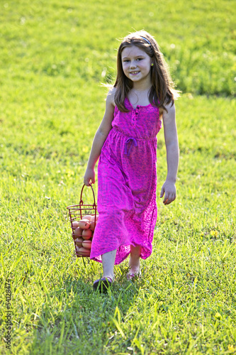 Photo: Young girl carrying brown eggs in a basket Young girl carrying brown eggs in a basket
