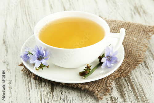 Photo: Cup of tea with chicory, on wooden background Cup of tea with chicory, on wooden background