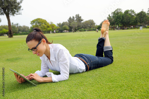 Photo: Beautiful young woman with tablet in park Beautiful young woman with tablet in park