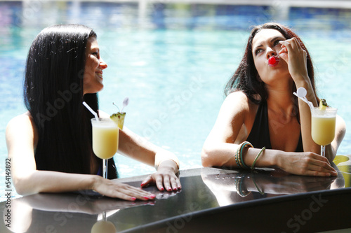 Photo: Two women with cocktails in swimming pool Two women with cocktails in swimming pool