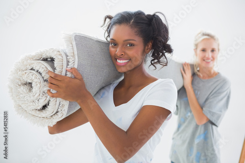 Photo: Happy housemates carrying rolled up rug Happy housemates carrying rolled up rug