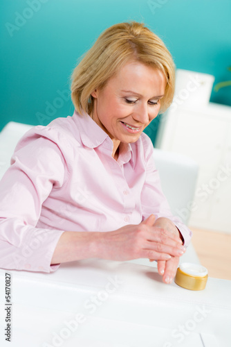 Photo: frau trägt handcreme auf frau trägt handcreme auf