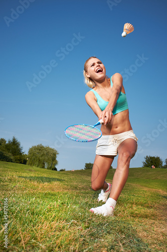 Photo: Fitness, young woman playing badminton in a city park Fitness, young woman playing badminton in a city park