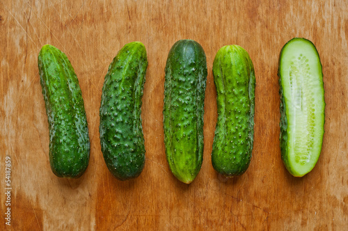 Photo: Cucumbers on a wooden table, one sliced Cucumbers on a wooden table, one sliced