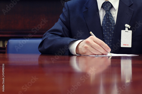 Photo: Journalist is doing paperwork at the conference Journalist is doing paperwork at the conference