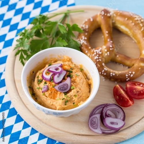 Photo: Pretzel with obatzda-cheese on wooden plate Pretzel with obatzda-cheese on wooden plate