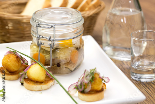 Photo: pickled herring in a glass jar with potato canapes pickled herring in a glass jar with potato canapes