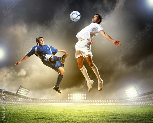 Photo: two football players striking the ball two football players striking the ball