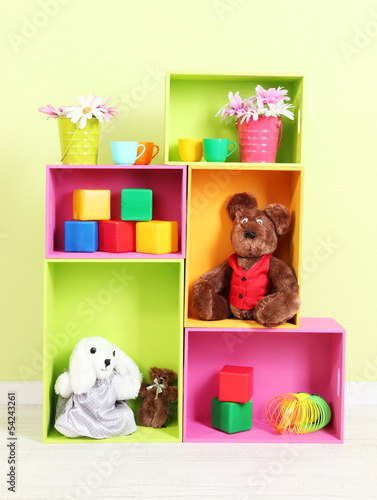 Photo: Bright shelves of different colors with toys on wall background Bright shelves of different colors with toys on wall background