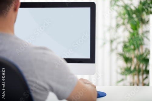 Photo: Man in front of computer, back view Man in front of computer, back view