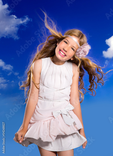 Photo: Blond girl with fashion dress blowing hair in blue sky Blond girl with fashion dress blowing hair in blue sky