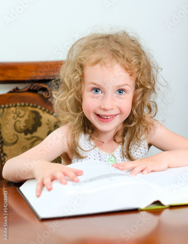 Photo: Cute little smiling girl reading a book Cute little smiling girl reading a book