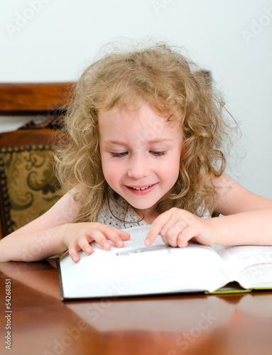 Photo: Cute little smiling girl reading a book Cute little smiling girl reading a book